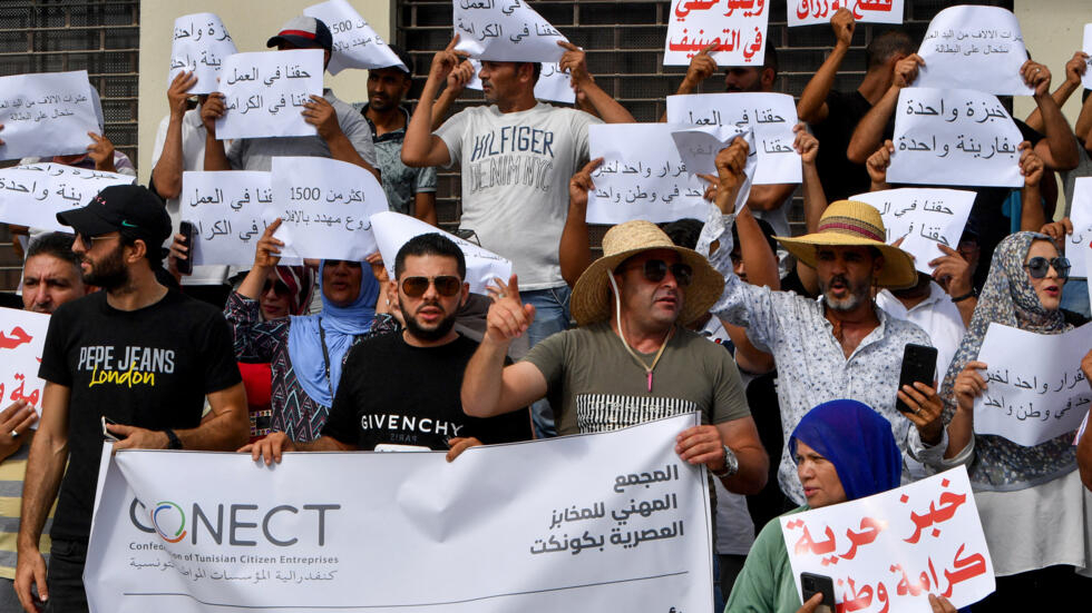 Demonstrators lift placards during a rally for bakery staff in front of the headquarters of the Ministry of Commerce in Tunis on August 7.